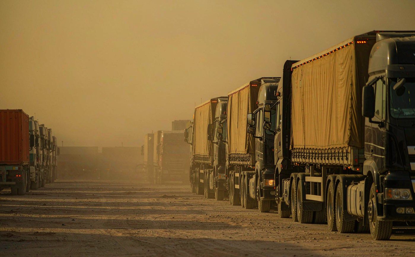Fleet of heavy trucks with LED marker lights in a Middle East desert logistics yard at dusk